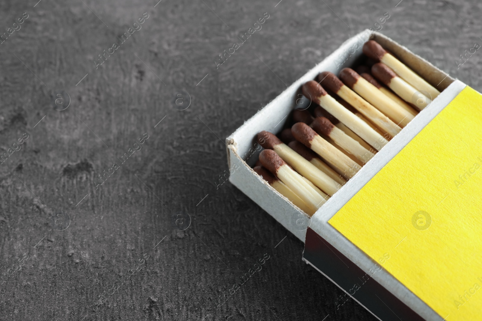 Photo of Open box with matches on grey background, space for text