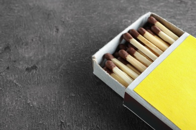 Open box with matches on grey background, space for text