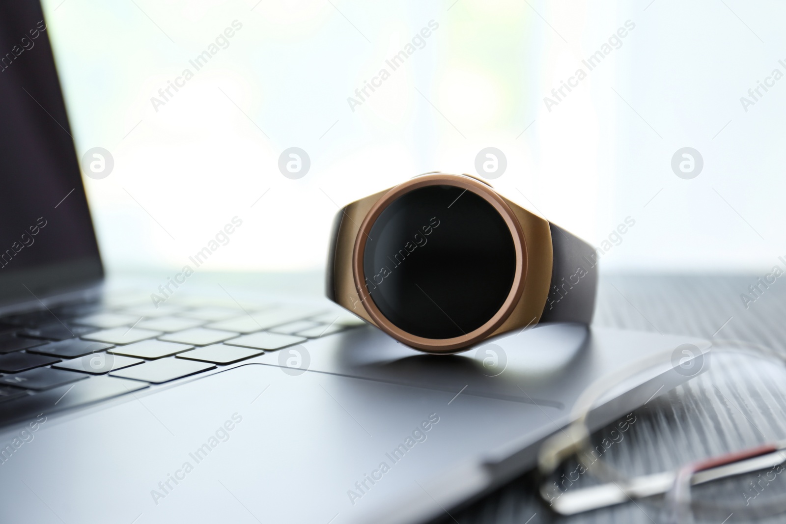 Stylish smart watch and laptop on table, closeup Photo of Stylish smart watch and laptop on table, closeup