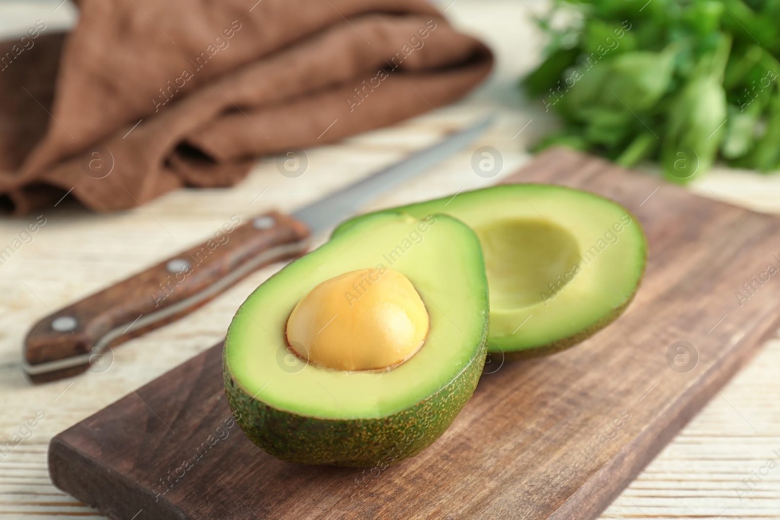 Photo of Wooden board with cut avocado on table