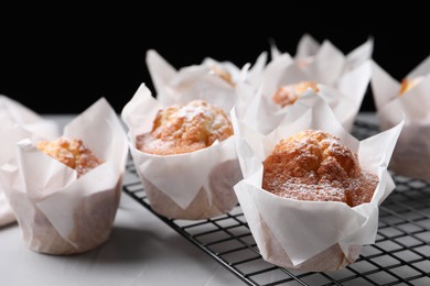 Delicious muffins with powdered sugar on light table, closeup