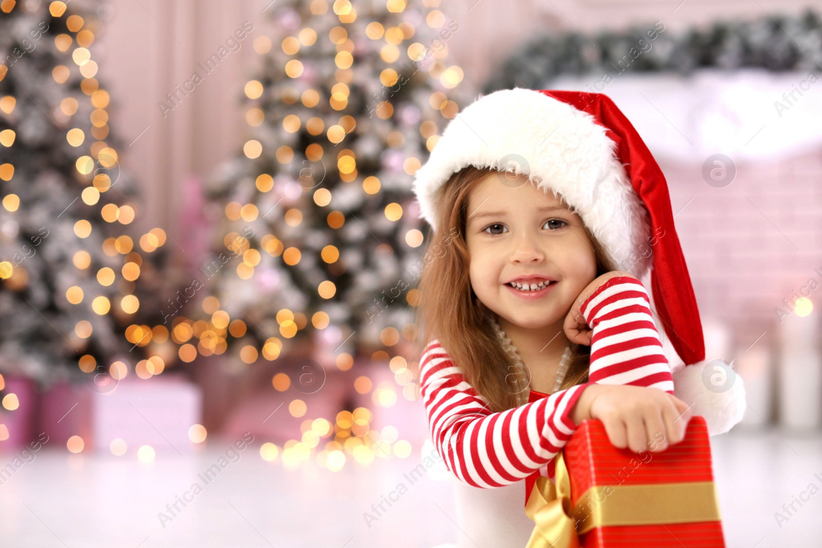 Photo of Cute little child with Christmas gift at home. Space for text