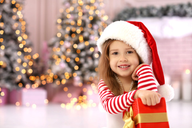 Photo of Cute little child with Christmas gift at home. Space for text