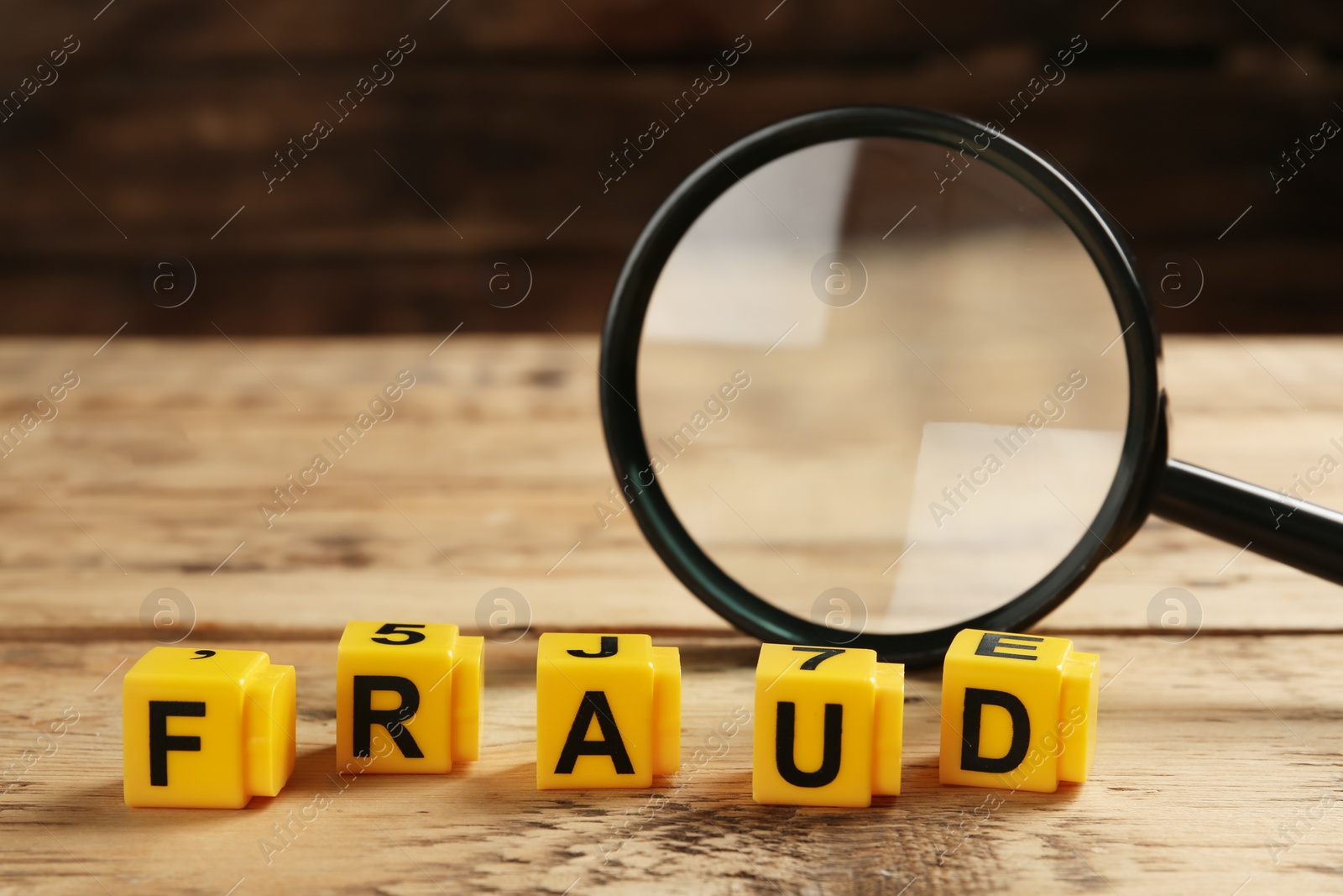 Photo of Yellow cubes with word Fraud and magnifying glass on wooden table. Space for text