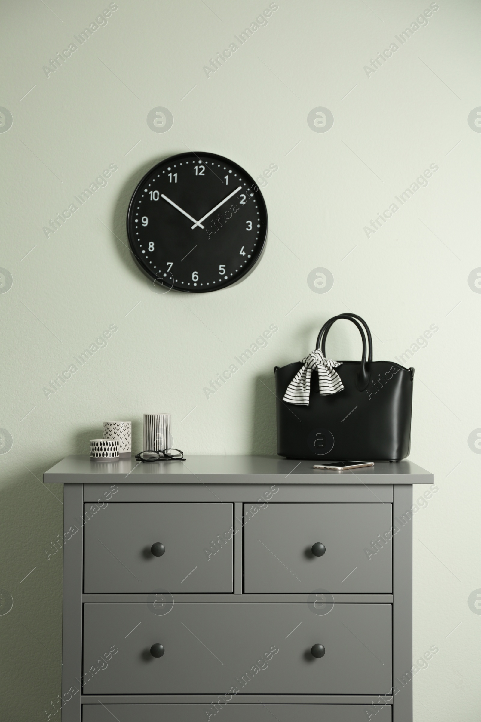 Photo of Grey chest of drawers near light wall in room