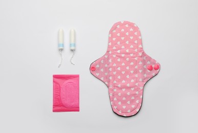 Disposable and reusable menstrual pads near tampons on white background, flat lay