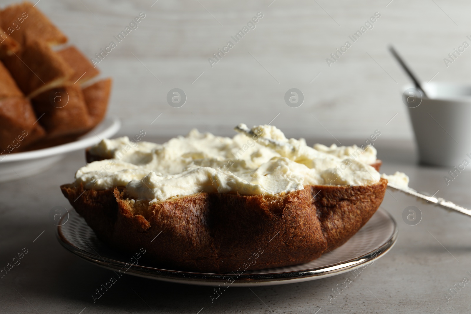 Photo of Slice of delicious Pandoro cake with cream on grey table
