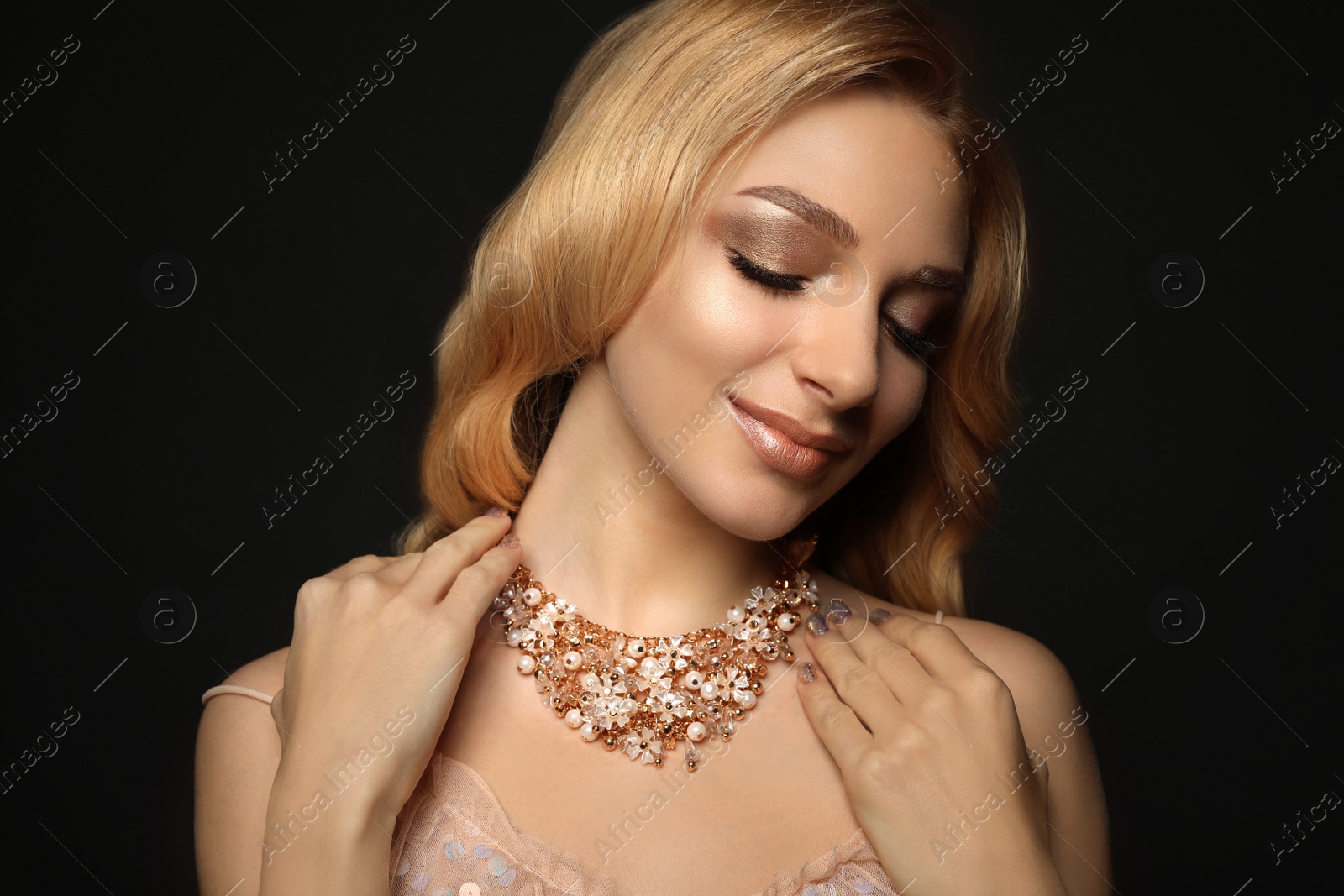 Photo of Beautiful young woman with elegant jewelry on dark background