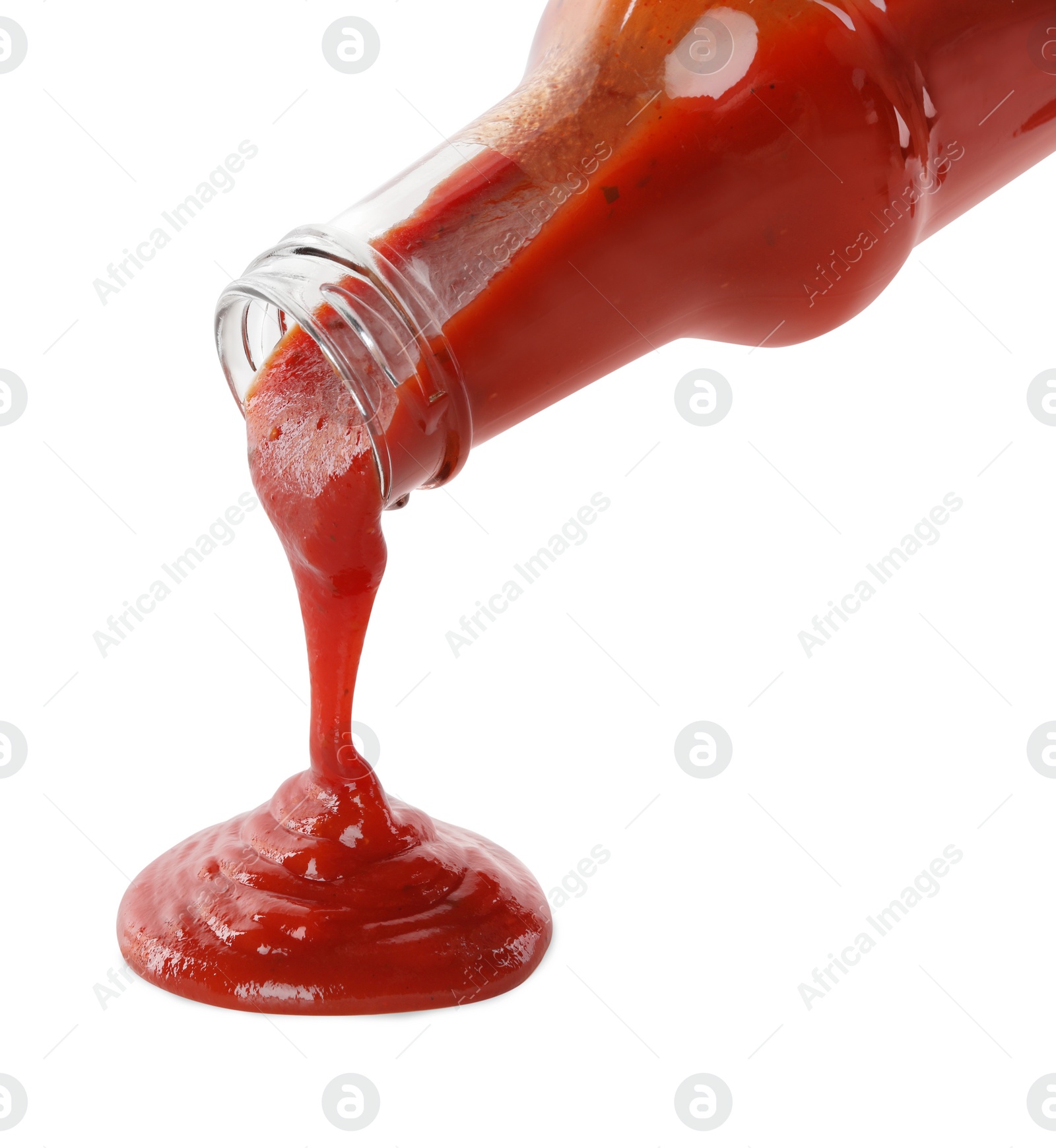 Photo of Pouring tasty ketchup from glass bottle on white background, closeup