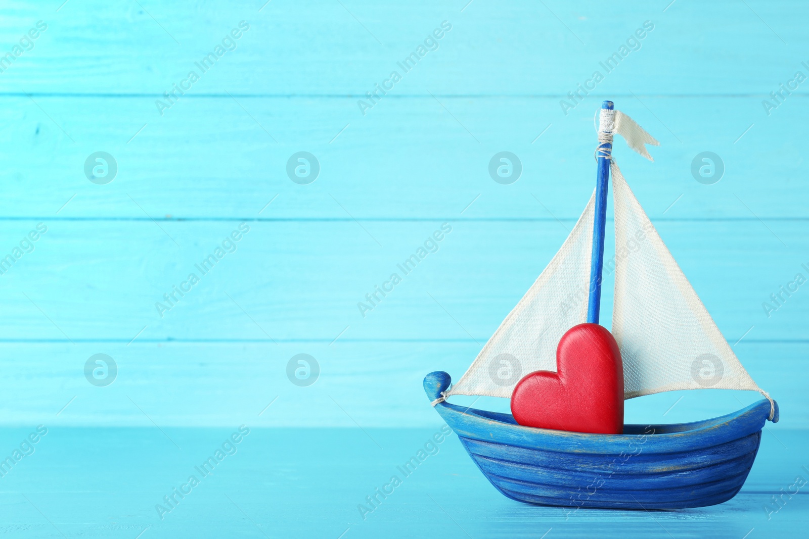 Photo of Toy boat with red heart on table against color background. Space for text