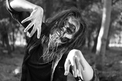 Photo of Scary zombie outdoors, black and white effect. Halloween monster