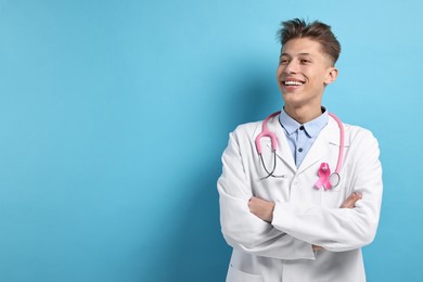 Mammologist with pink ribbon on light blue background, space for text. Breast cancer awareness