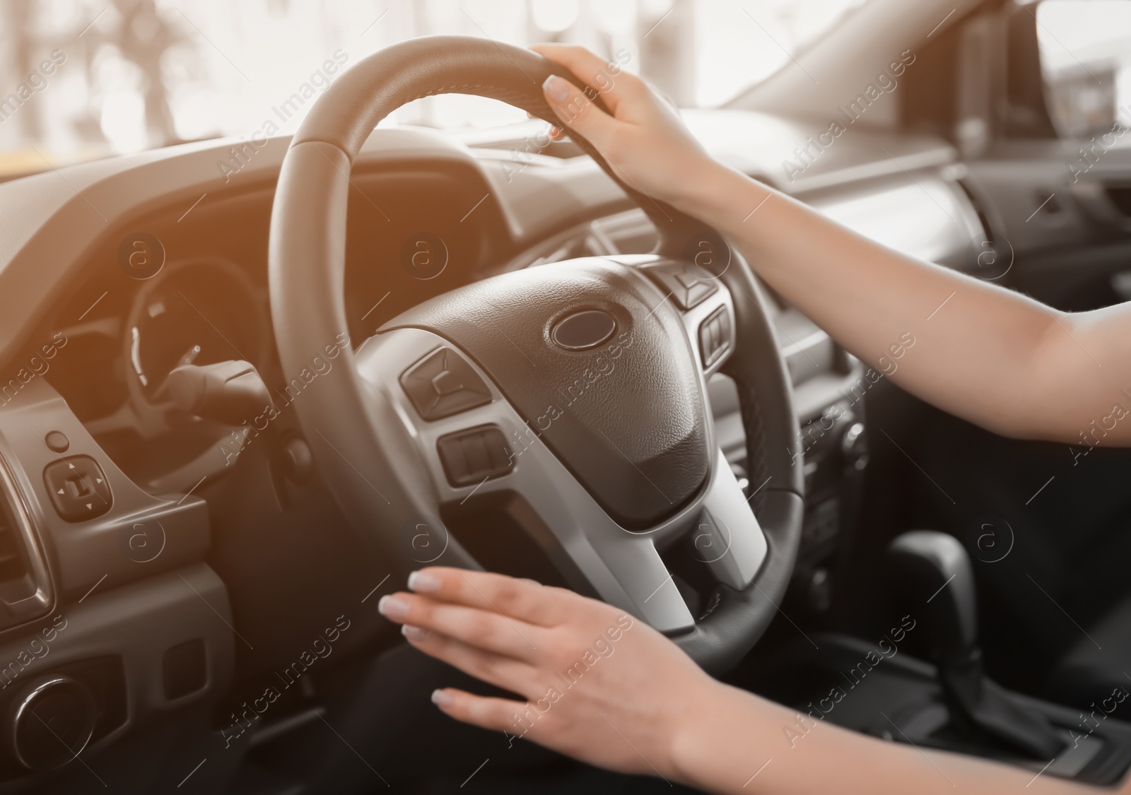 Photo of Young woman sitting in driver's seat of new car at salon