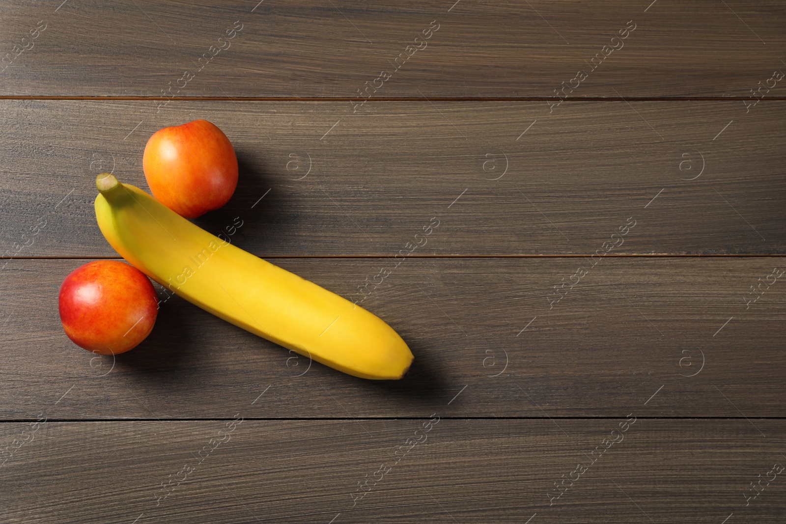 Photo of Banana and nectarines symbolizing male genitals on wooden table, flat lay with space for text. Potency concept