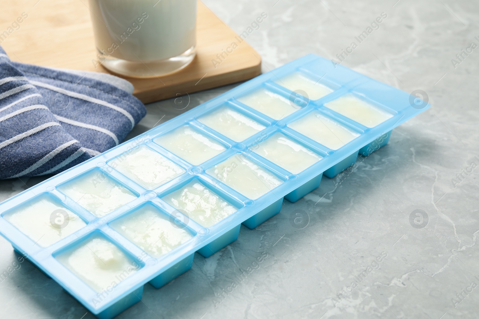 Photo of Ice cube tray with frozen milk on grey table