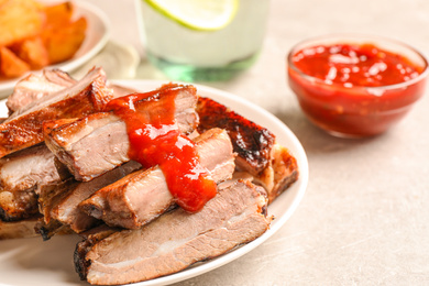 Delicious grilled ribs with sauce on light grey table, closeup