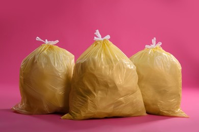 Trash bags full of garbage on pink background