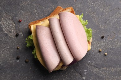 Photo of Delicious sandwich with boiled sausage and cheese on grey textured table, flat lay