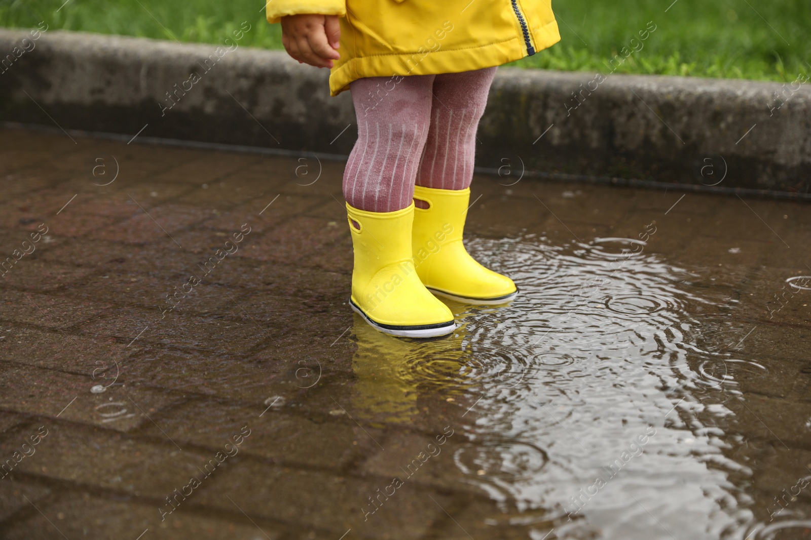 Photo of Girl walking in puddle outdoors on rainy weather, closeup