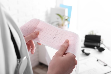 Doctor examining cardiogram in medical clinic, closeup