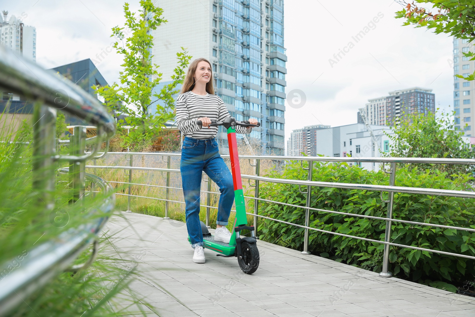 Photo of Happy woman with modern electric kick scooter on city street, space for text