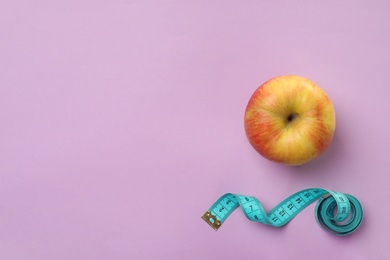 Photo of Fresh apple and measuring tape on color background, top view. Healthy diet