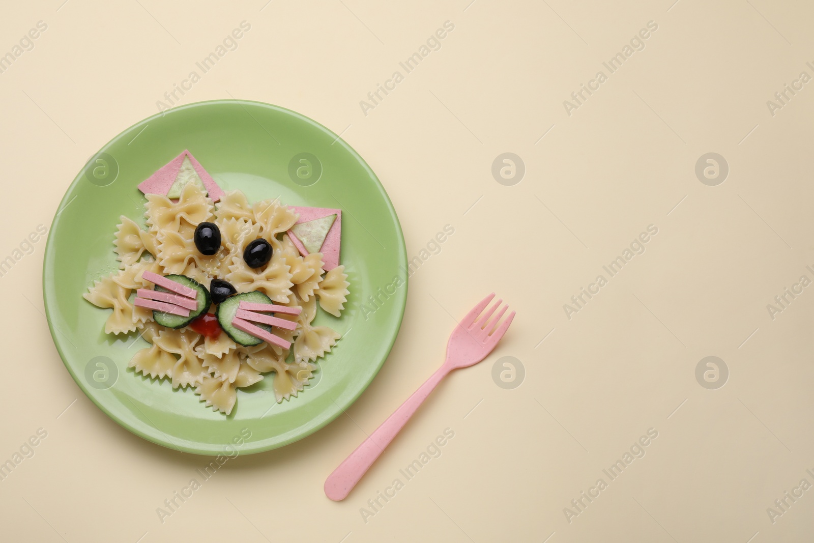 Photo of Creative serving for kids. Plate with cute cat made of tasty pasta, vegetables and sausage on beige background, flat lay. Space for text