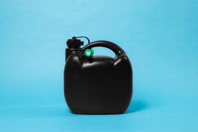 Photo of New black plastic canister on light blue background