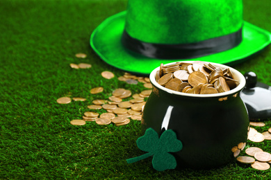 Photo of Pot of gold coins and clover on green grass, space for text. St. Patrick's Day celebration