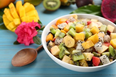 Delicious exotic fruit salad on light blue wooden table