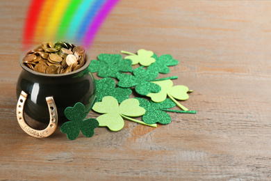 Pot with gold coins, horseshoe and clover leaves on wooden table. St. Patrick's Day celebration