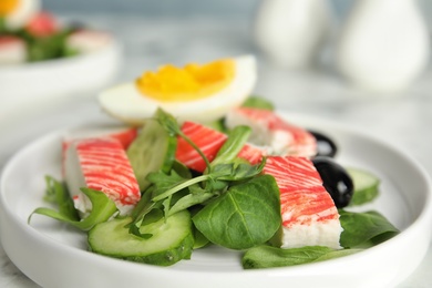 Photo of Delicious crab stick salad on white plate, closeup