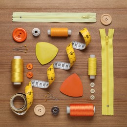 Flat lay composition with different sewing accessories on wooden background