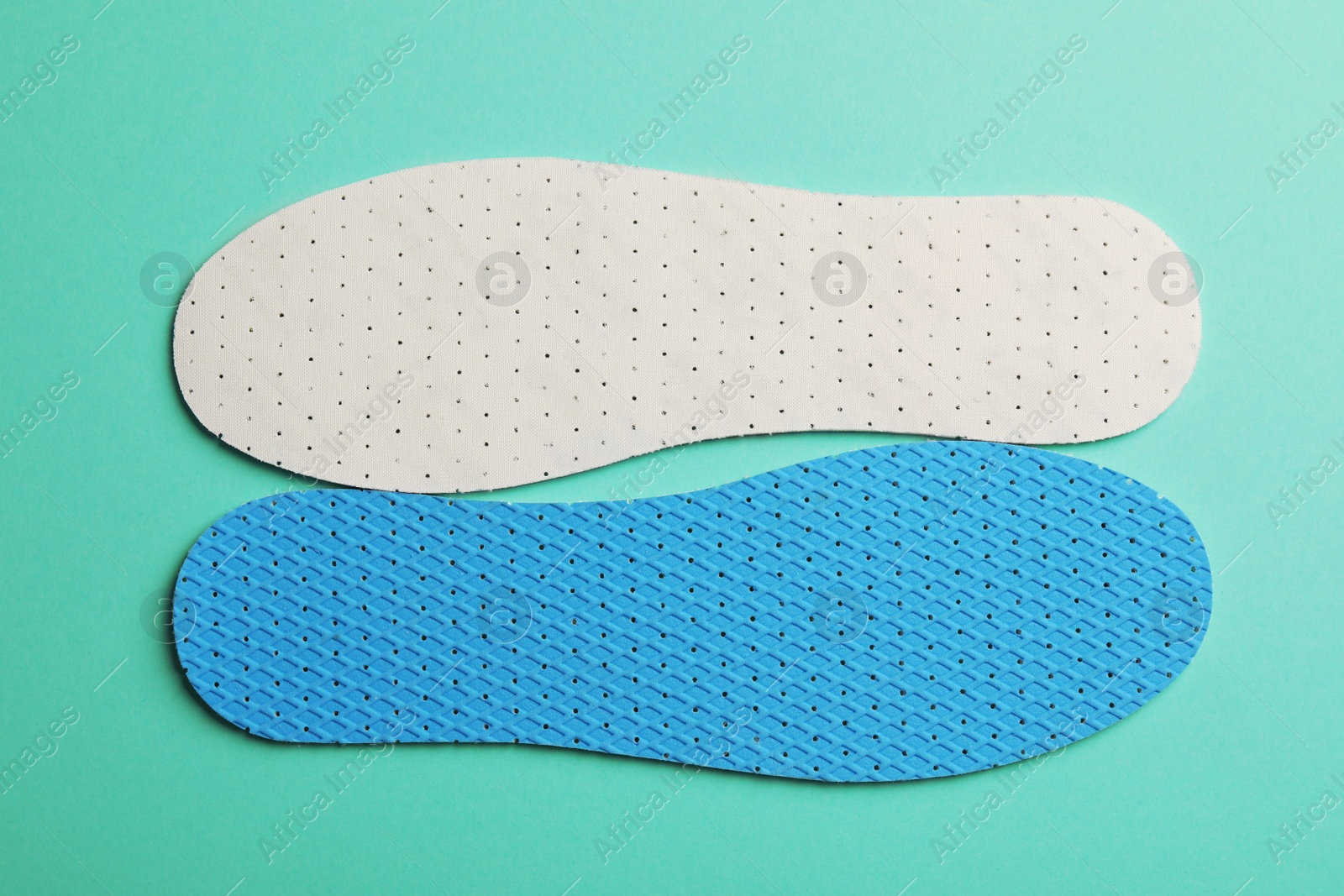 Photo of Pair of breathable shoe insoles on turquoise background, flat lay