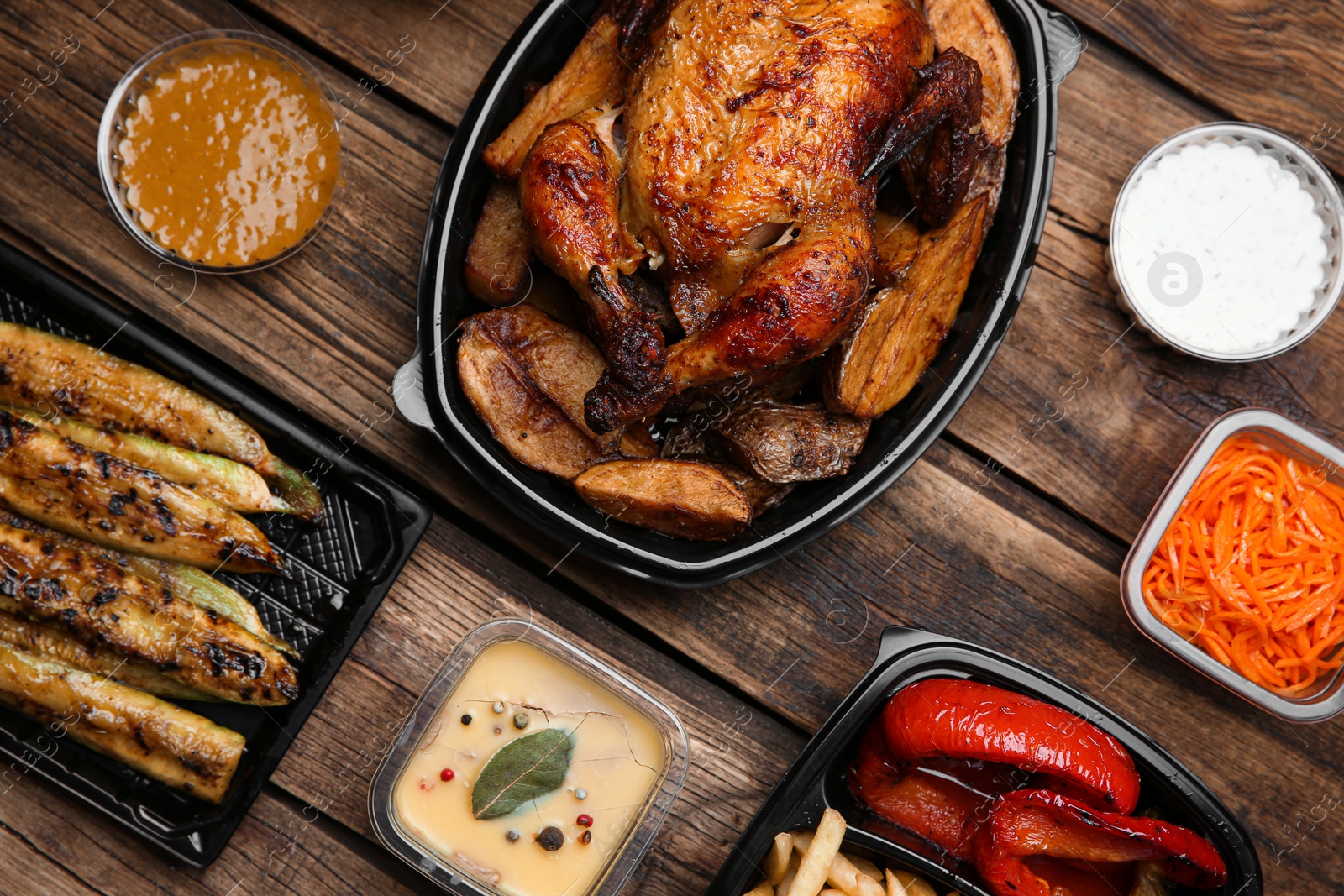 Photo of Plastic containers with different dishes on wooden table, flat lay. Food delivery service