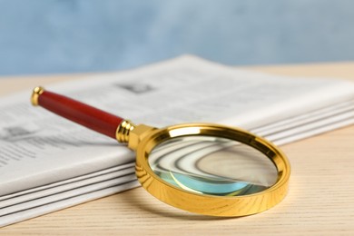 Stack of newspapers and magnifier on wooden table. Search concept