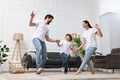 Happy family dancing in living room, low angle view