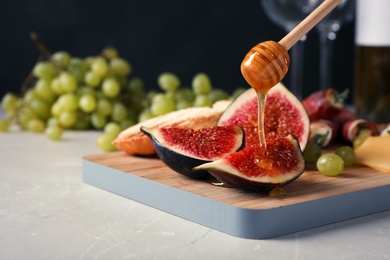 Photo of Pouring honey onto ripe fig slices on wooden board, closeup