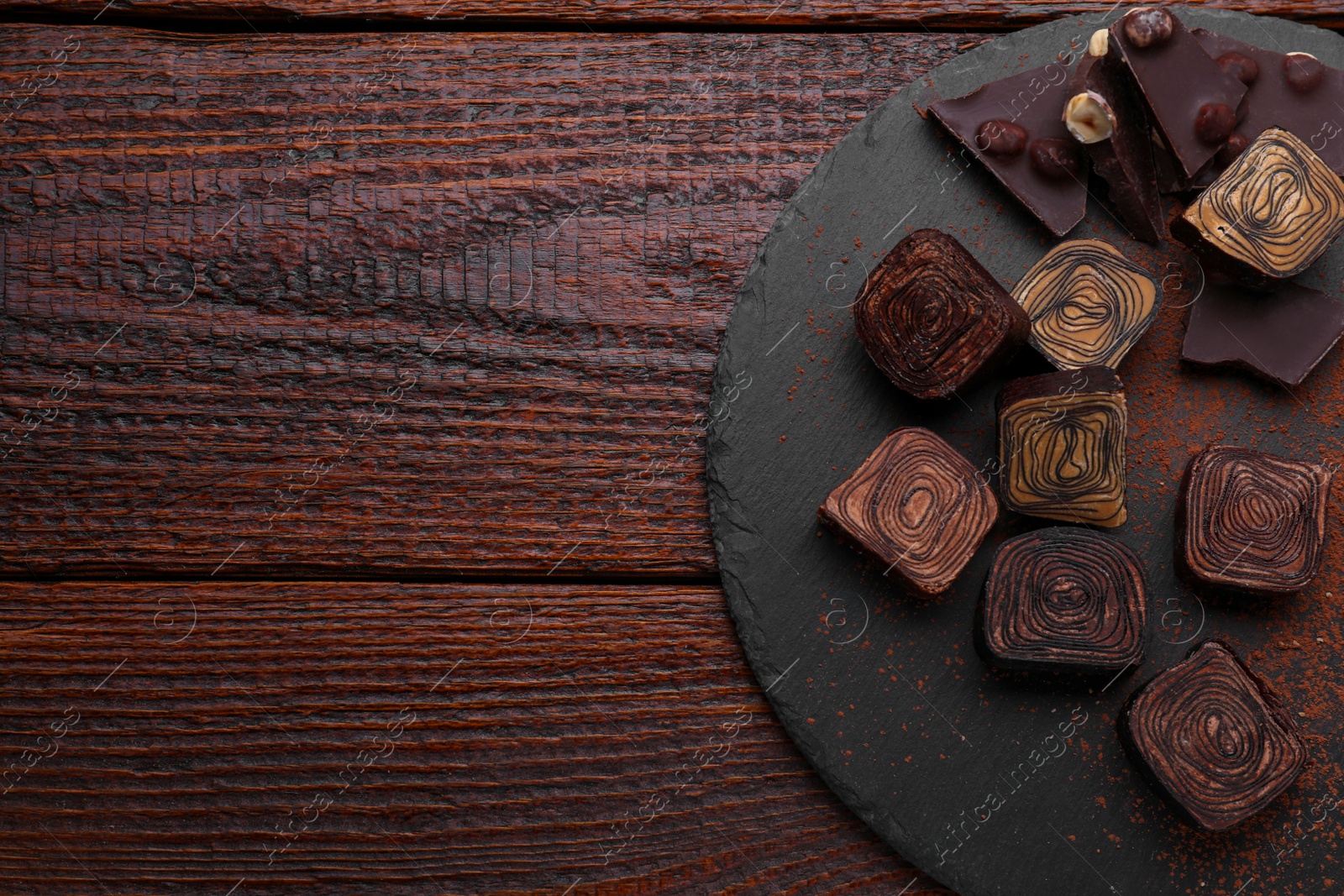 Photo of Different tasty chocolate candies on wooden table, flat lay. Space for text