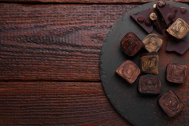 Photo of Different tasty chocolate candies on wooden table, flat lay. Space for text