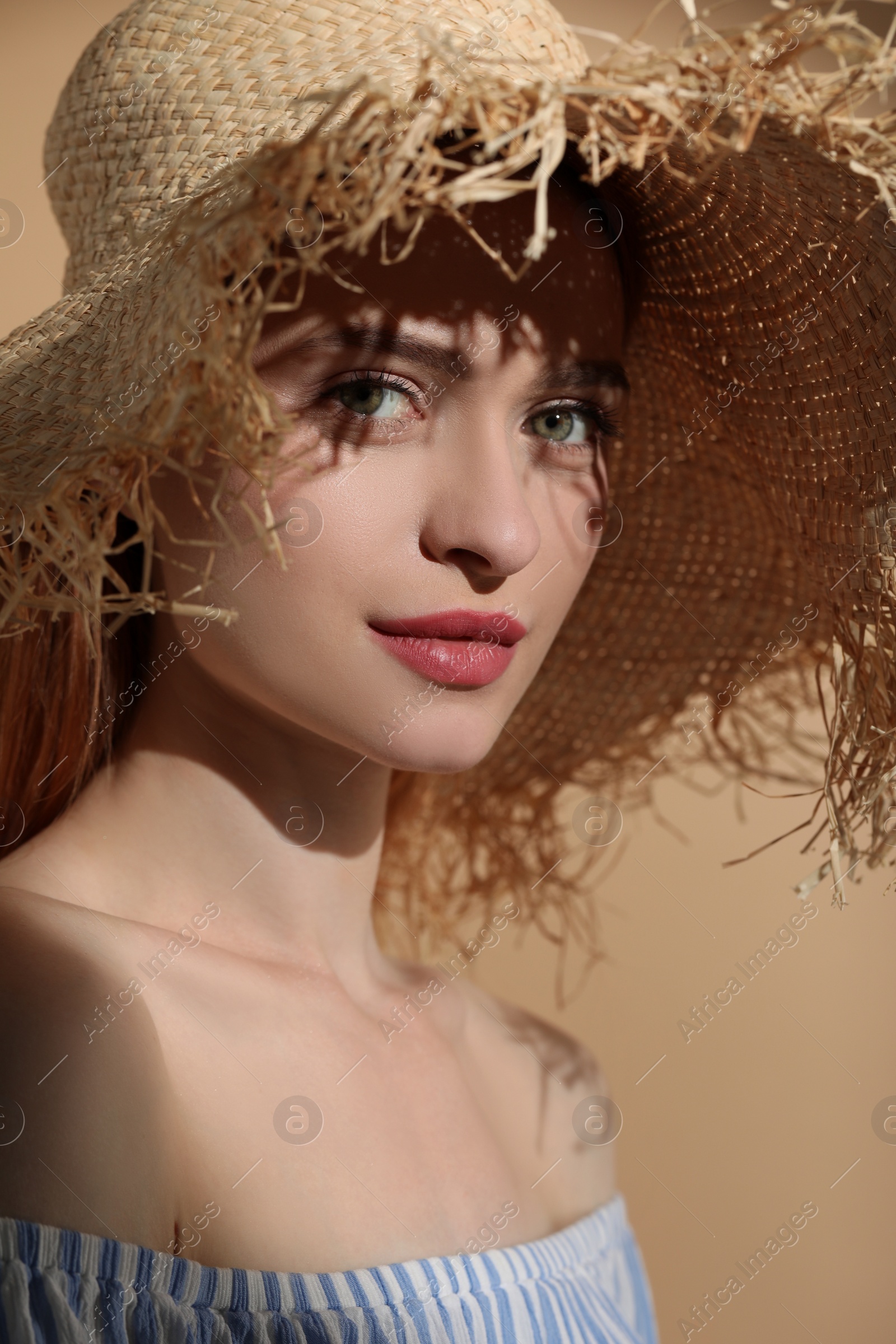 Photo of Beautiful young woman in sunlight on beige background