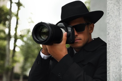 Private detective with modern camera spying on city street