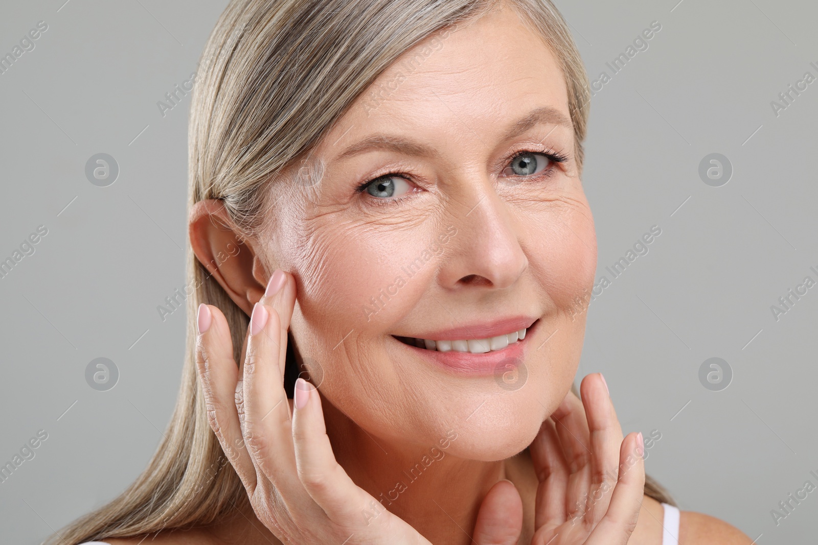 Photo of Beautiful mature woman with healthy skin on gray background