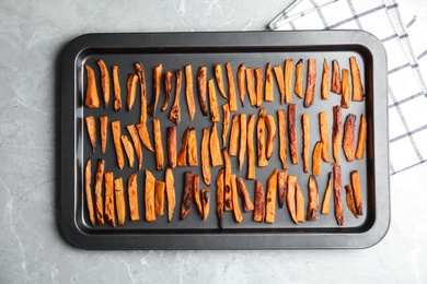 Photo of Baking sheet with sweet potato slices on grey background, top view