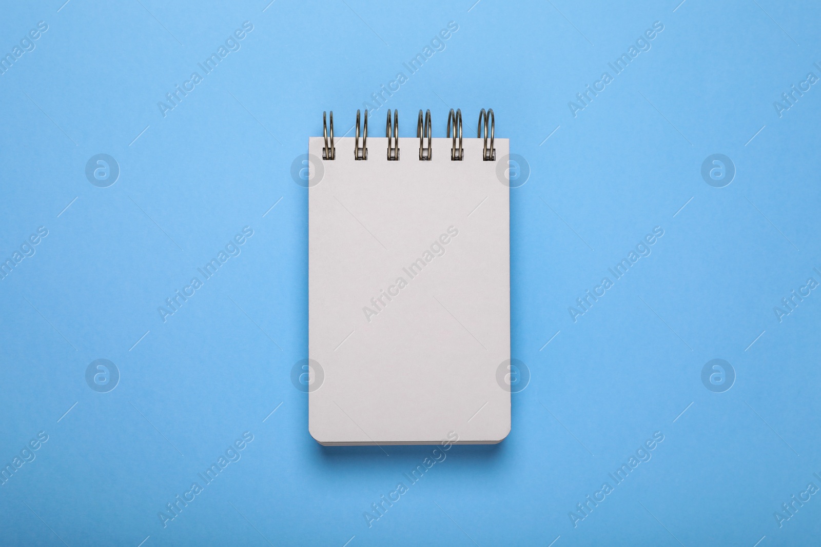 Photo of Open blank notebook on light blue background, top view