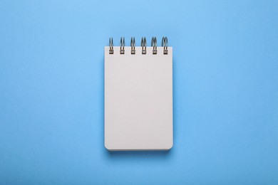 Photo of Open blank notebook on light blue background, top view