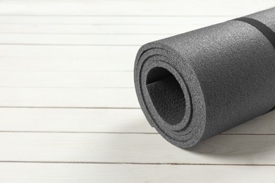 Photo of Yoga mat on white wooden floor, closeup. Space for text
