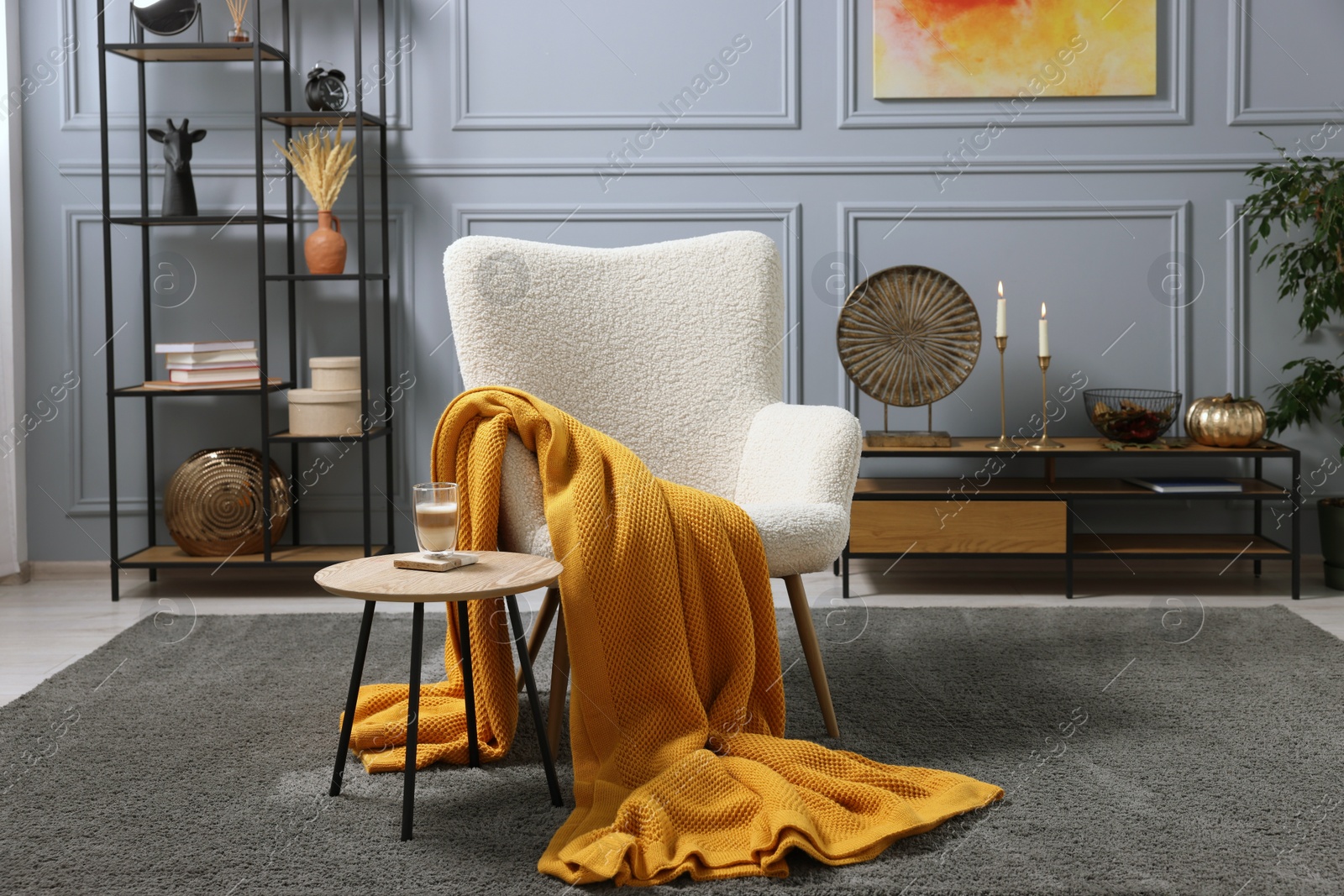 Photo of Living room interior with comfortable armchair, blanket and side table