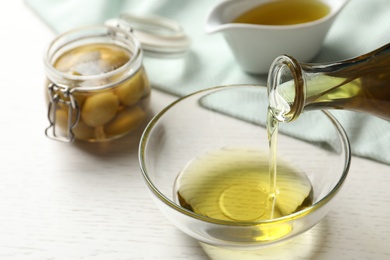 Pouring fresh olive oil into bowl on table