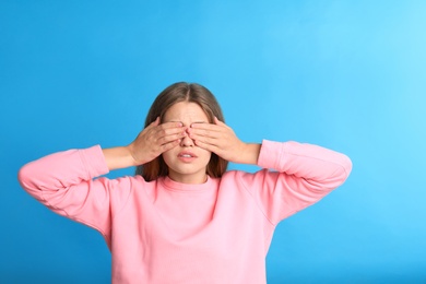 Young woman being blinded on blue background